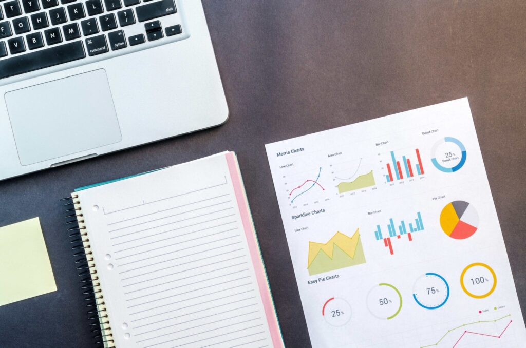 Rapport d’analyse avec graphiques de performance posé sur un bureau à côté d’un ordinateur portable