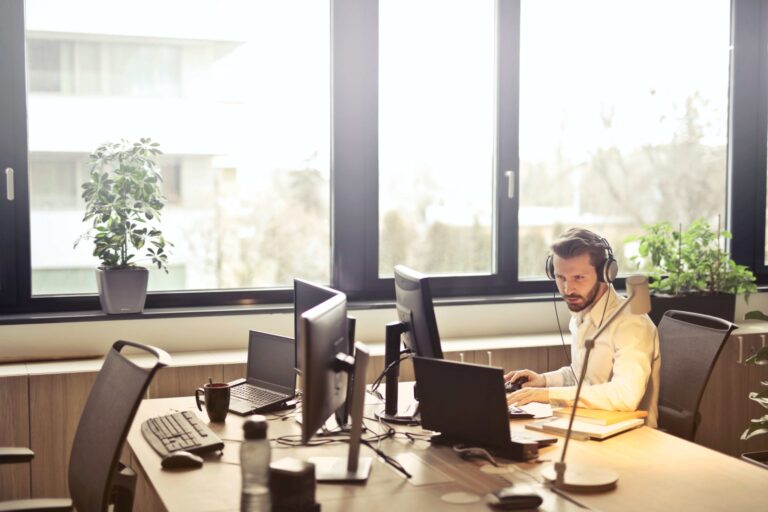 Technicien support travaillant sur plusieurs écrans dans un bureau équipé de matériel informatique