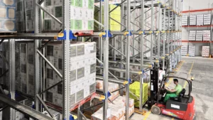 Un entrepôt où un employé utilise un chariot élévateur pour organiser les palettes selon la définition de la méthode FIFO, garantissant que les premiers produits entrés sont les premiers à sortir.