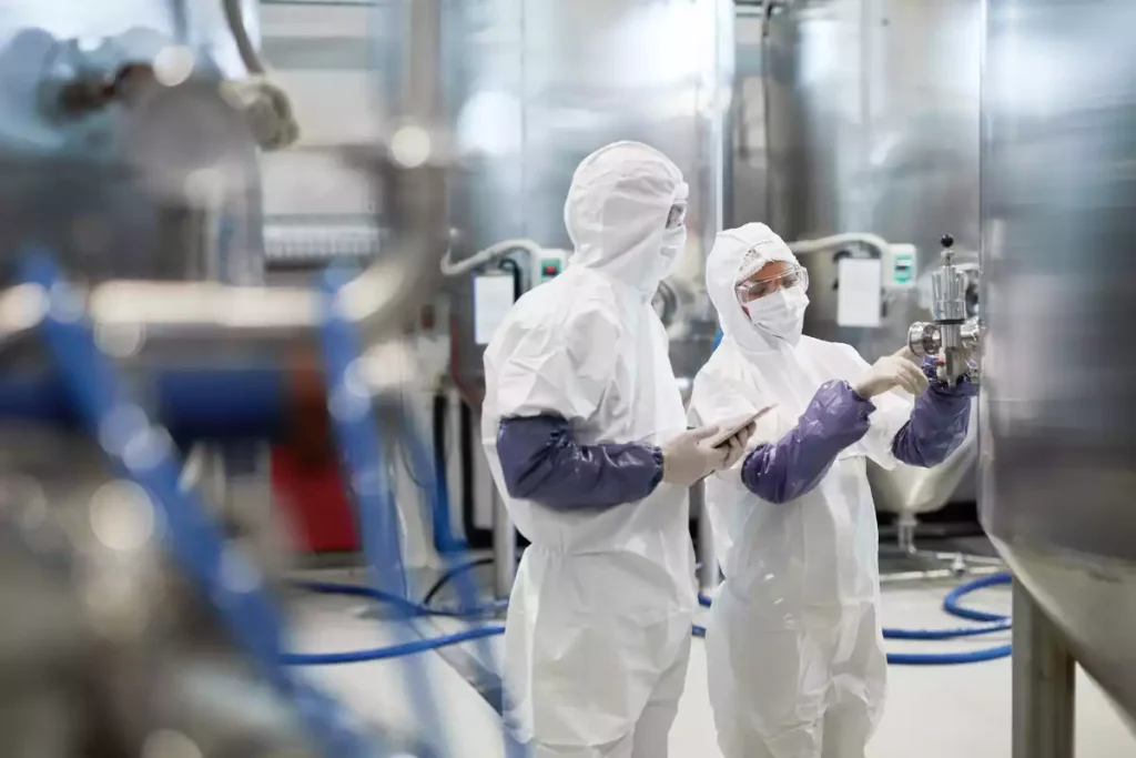 Techniciens en salle blanche contrôlant des équipements industriels dans un environnement pharmaceutique