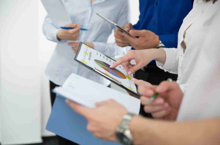Gros plan de deux professionnels se serrant la main au-dessus d'une table couverte de rapports avec graphiques et données financières, tablette en main