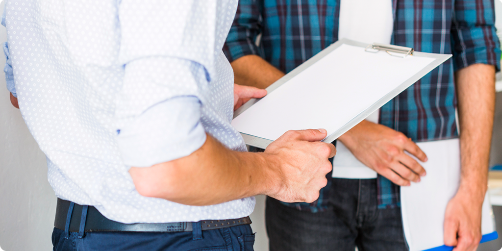Deux professionnels échangeant un document sur presse-papiers lors d'une réunion de travail