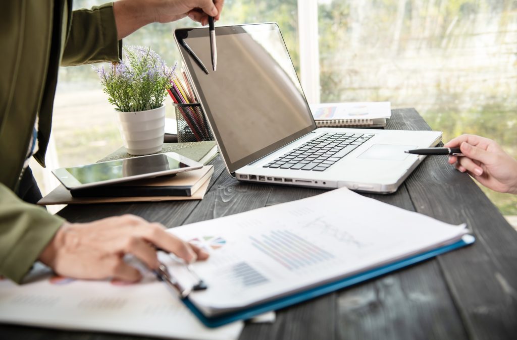 business woman hands using laptop computer placed messy office desktop scaled