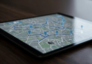 Tablette posée sur une table affichant une carte de navigation avec des épingles de localisation bleues et un itinéraire tracé