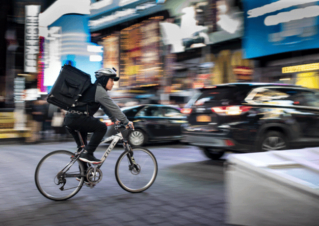 Un coursier brave la circulation dense et les lumières de New York pour assurer une livraison rapide en plein cœur de Manhattan.